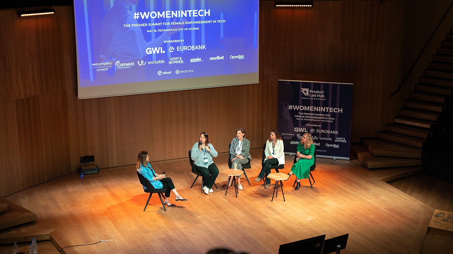 Panel discussion on stage at the #WomenInTech summit at Technopolis, Athens, with OpenBet among the sponsors on screen
